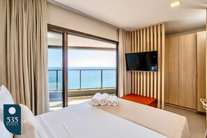 Ein Hotelzimmer mit Bett, Fernseher, Meerblick und einem Balkon.