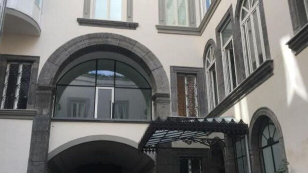 A building with a central arched entrance, multiple windows, and a decorative metal canopy. - Wonderful Holiday Home in the Historic Center of Naples in Piazza Bellini (Napoli)
