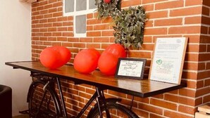 A brick wall with a window, a table with three red balloons, a framed certificate, and a bicycle. - Wonderful Holiday Home in the Historic Center of Naples in Piazza Bellini (Napoli)