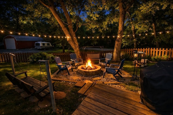 Gather in the backyard around the firepit with comfortable chairs and a swing, perfect for cozy evenings, shared stories, and relaxing under the stars.