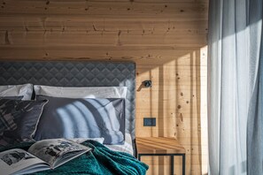 A bedroom with a wooden headboard, a bed with pillows, a blanket, and an open book. - 'Pino Mugo' Apartment with Mountain View, Wi-Fi and Air Conditioning (Cavedago)