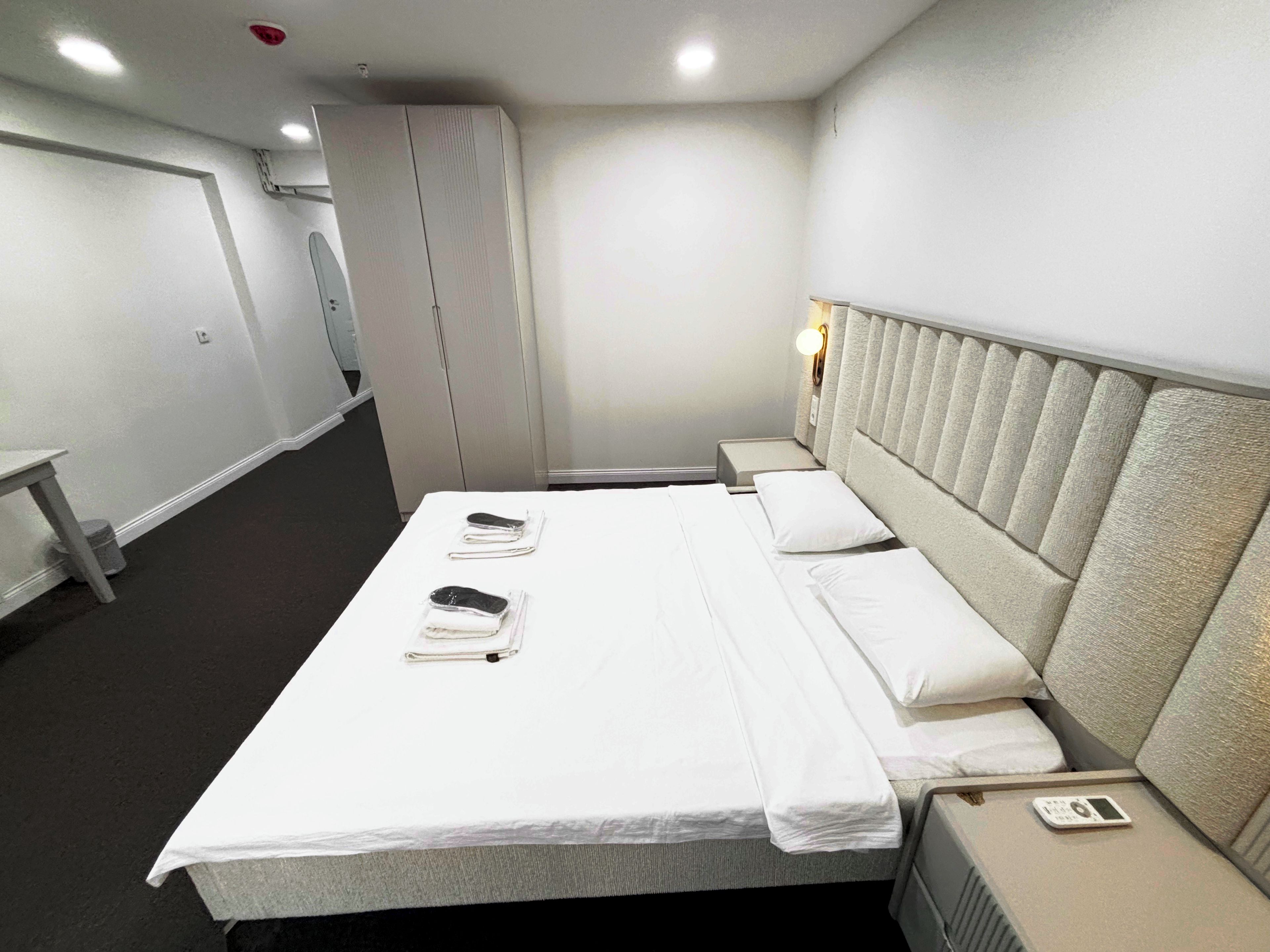 A hotel room with a bed, bedside tables, and a headboard.