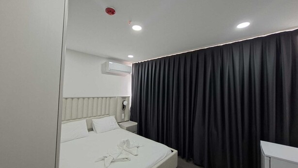 A hotel room with a bed, a bedside table, a nightstand, a wall-mounted air conditioner, and a black curtain. - Zeynus Hotel Kadıköy (İstanbul)