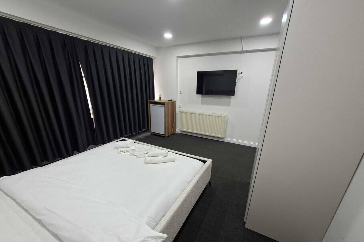 Ett hotellrum med en säng, en tv, ett skrivbord och ett element.