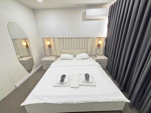 A hotel room with a bed, two bedside tables, a mirror, and an air conditioning unit. - Zeynus Hotel Kadıköy (İstanbul)