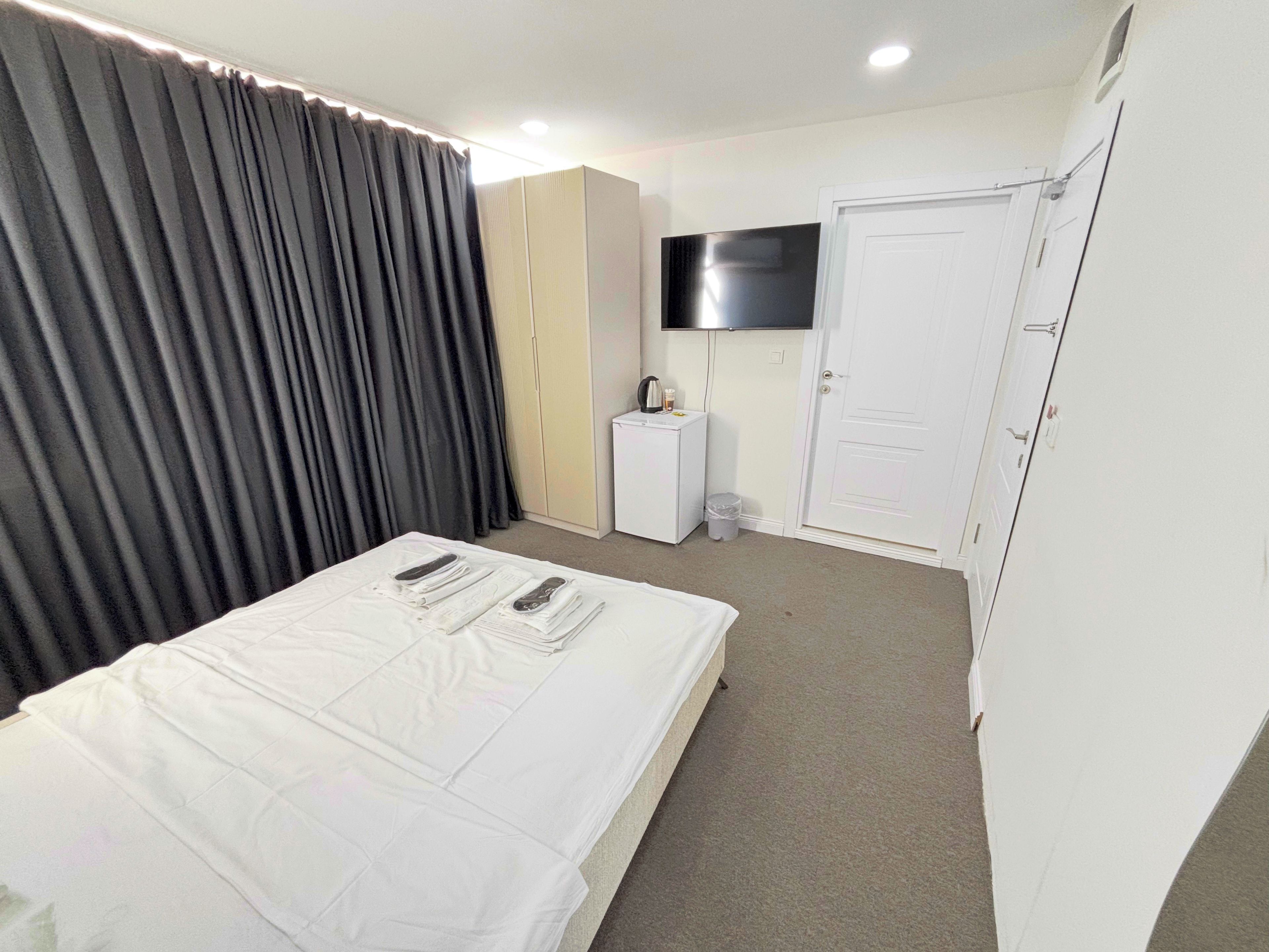 Ein Hotelzimmer mit einem Bett, einem Fernseher, einem kleinen Nachttisch, einem Schrank und einer Tür.