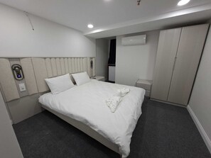 Et moderne hotelværelse med en stor seng, et natbord, en garderobe og en aircondition.