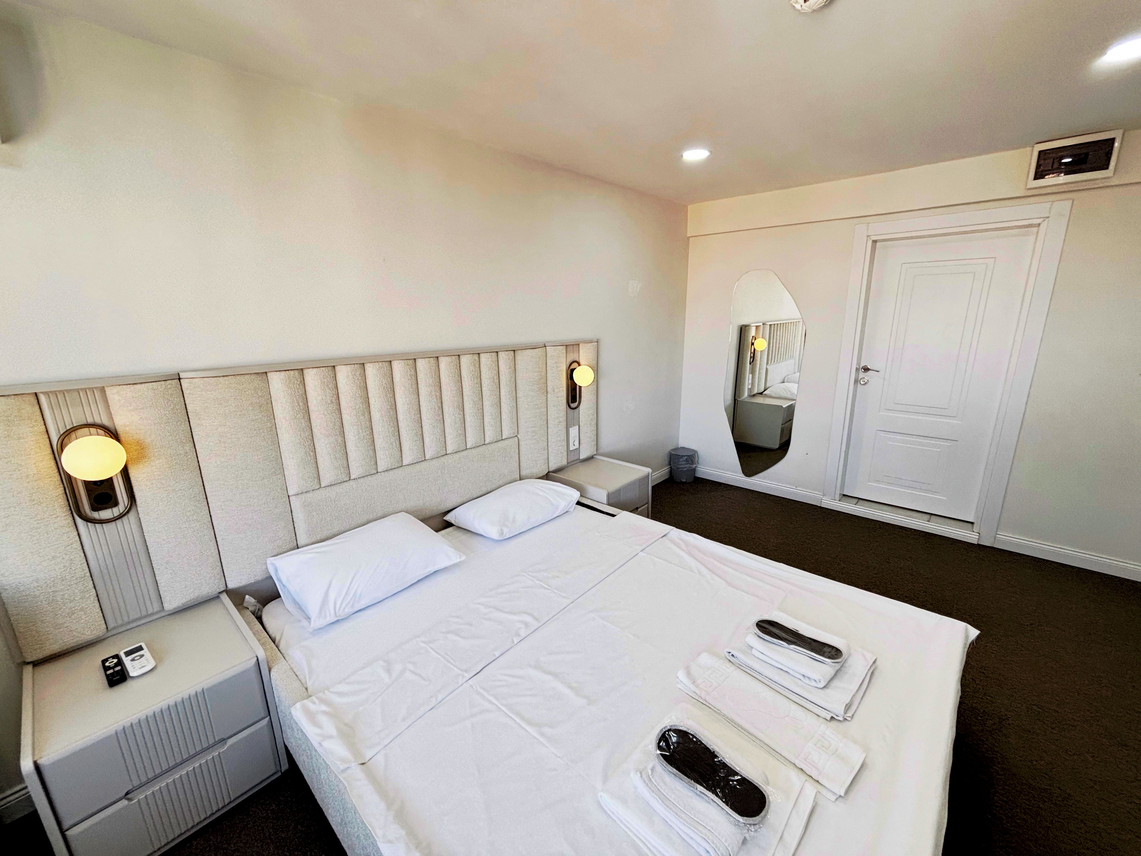 Une chambre d’hôtel avec un grand lit, des tables de chevet, un miroir et une armoire.
