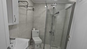 A modern bathroom with a glass-enclosed shower, a white sink, and a toilet. - Zeynus Hotel Kadıköy (İstanbul)