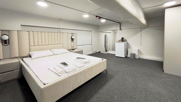 Ett modernt hotellrum med en stor säng, sängbord, ett skrivbord och en garderob.