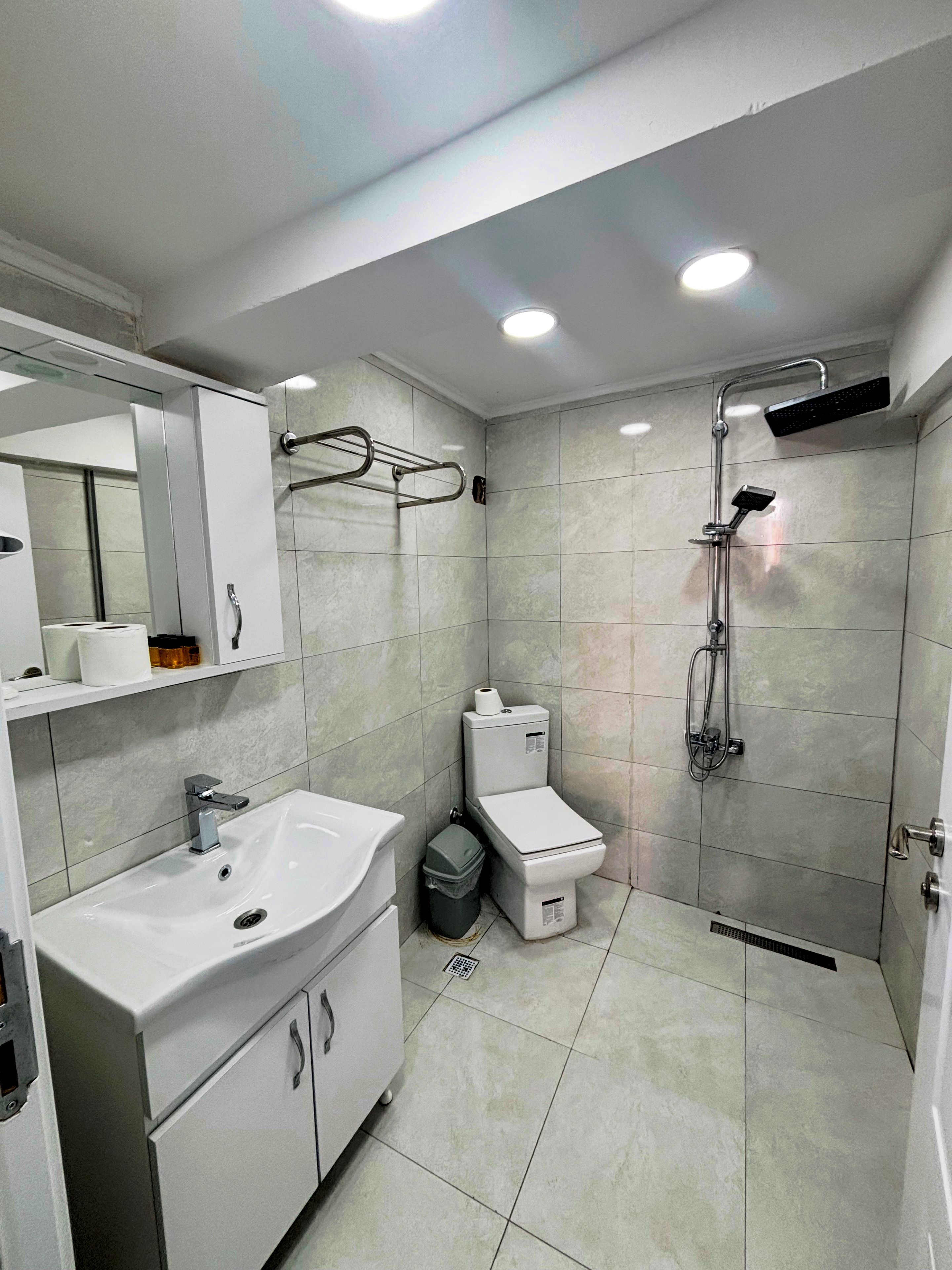 Un baño moderno con lavamanos, inodoro y ducha.