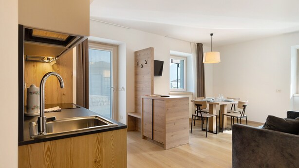 Una cocina moderna con un lavamanos, armarios de madera y un comedor con una mesa y sillas.