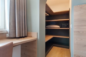 Ein Zimmer mit Schreibtisch, Bett und Einbauschrank.