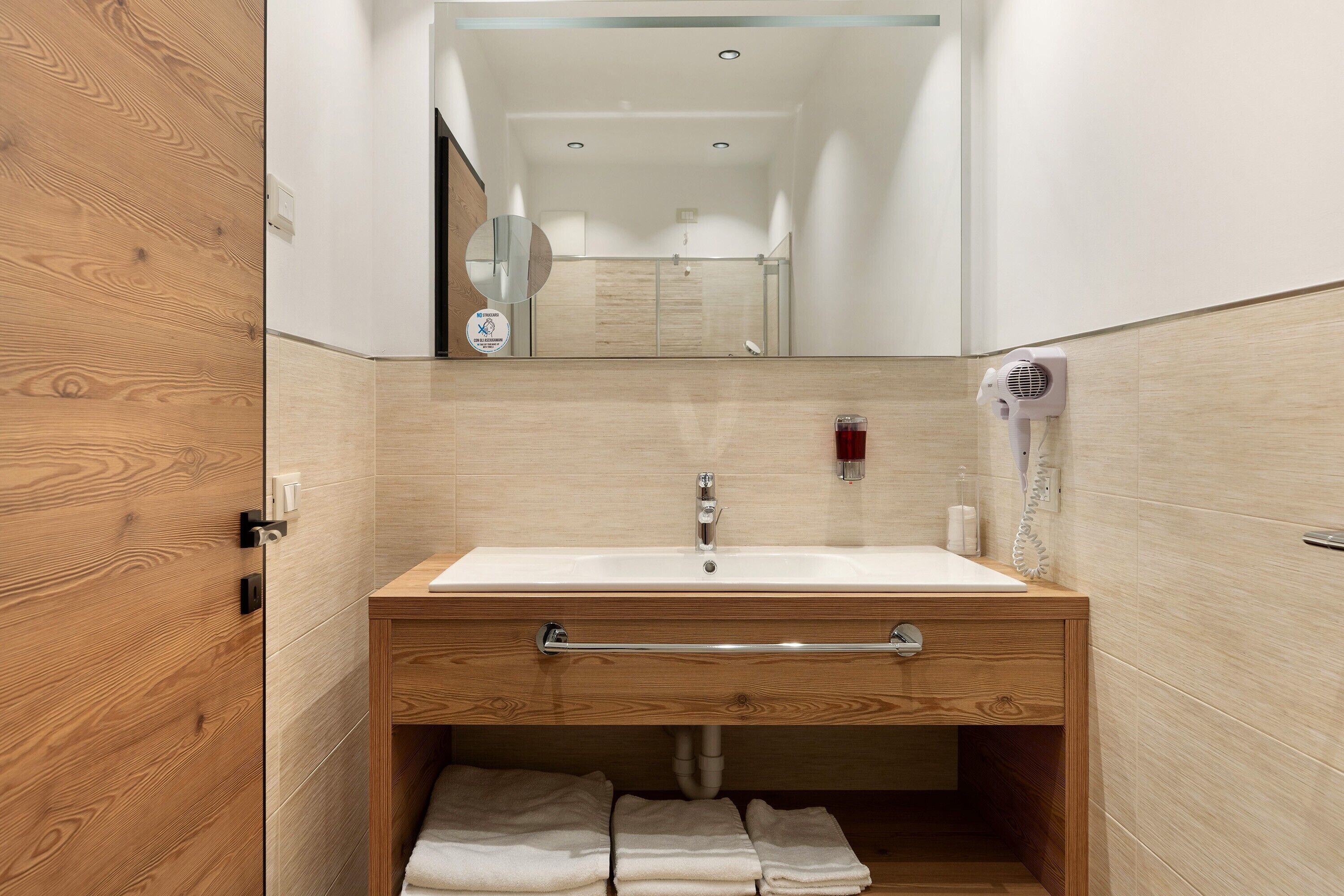 A bathroom with a wooden vanity, a sink, a towel rack, and a mirror.