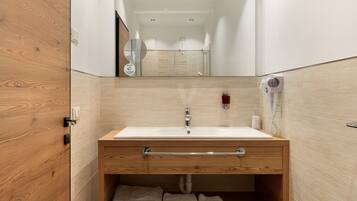 A bathroom with a wooden vanity, a sink, a towel rack, and a mirror.