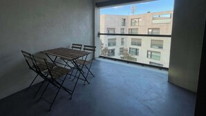 A balcony with a table and chairs, a view of a building, and a clear sky. - Apt near City Center, Novartis & Messe+Basel Card (Basel)
