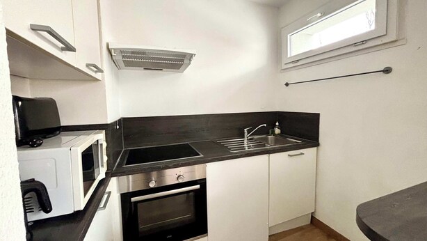 Una cocina compacta con microondas, horno, pileta y una ventana sobre la pileta.