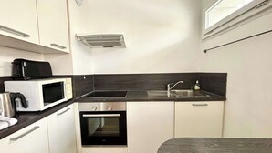 Una cocina compacta con microondas, estufa y pileta.
