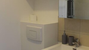 Un baño con inodoro, lavabo, espejo y ducha.