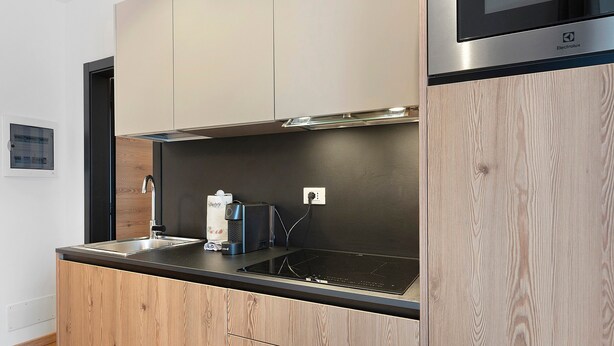 A modern kitchen with wooden cabinetry, a stainless steel range hood, and a built-in microwave.