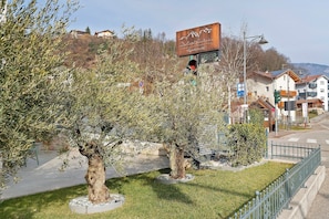 Uma rua com uma placa da 'Dolce & Gabbana', calçada arborizada e edifícios residenciais.