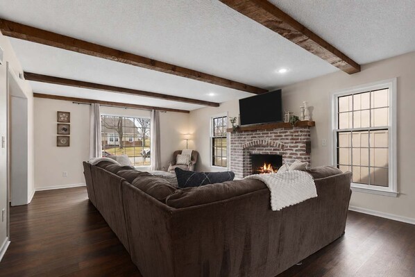 A living room with a fireplace, a sofa, a television, and a large window.