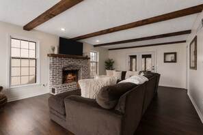 A living room with a fireplace, a sofa, and a large window.