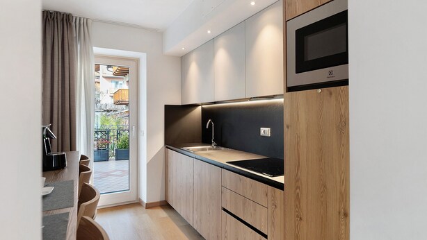 A modern kitchen with wooden cabinets, a black countertop, and a built-in microwave.