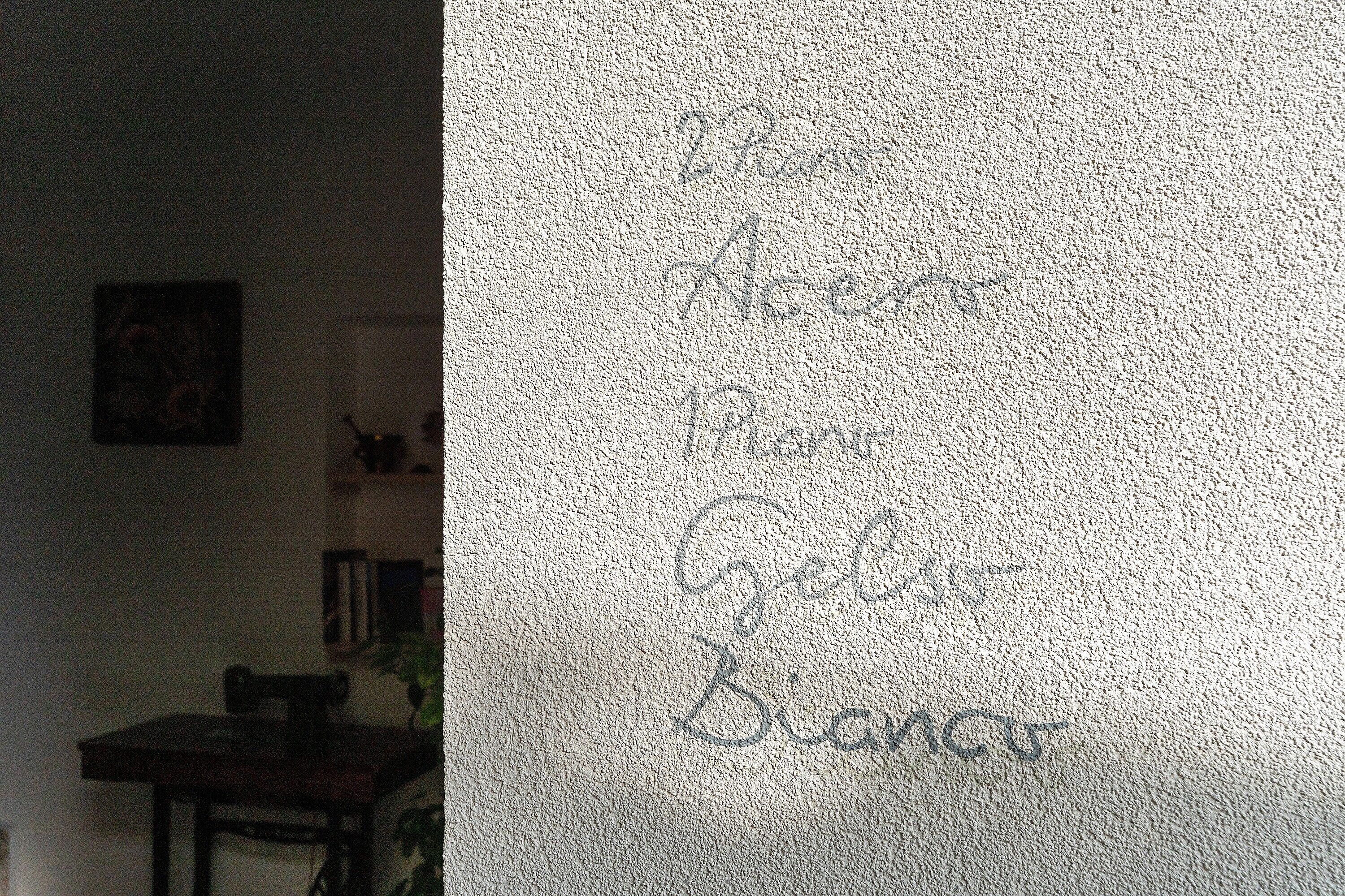 Eine strukturierte Wand mit undeutlich geschriebenen Inschriften.