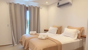 A modern hotel room with two beds, a ceiling air conditioner, and a view of the outdoors. - Apartamento Messina  (Jijoca de Jericoacoara)
