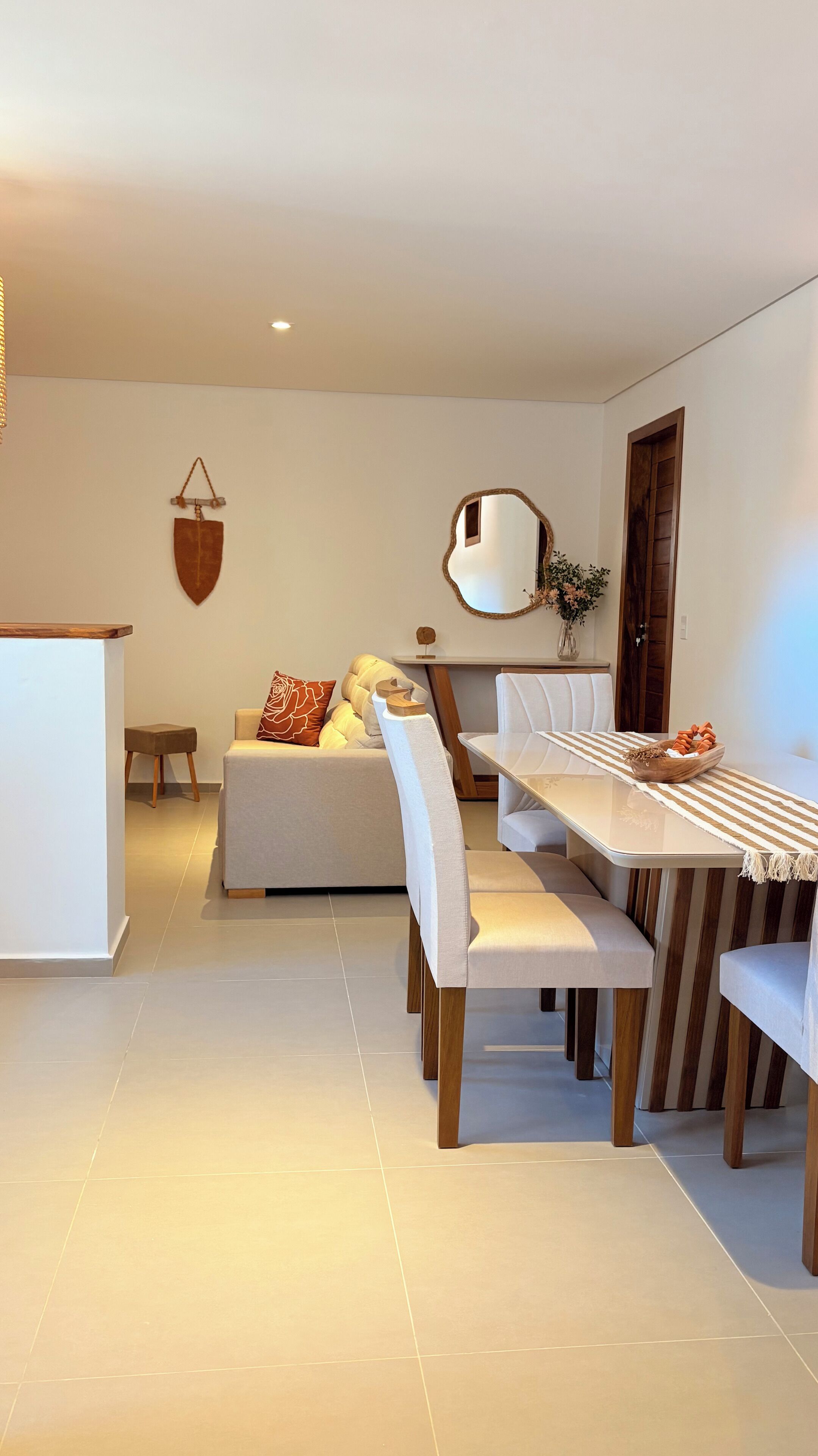 Un comedor moderno con una mesa larga, sillas con cojines y un sofá al fondo.