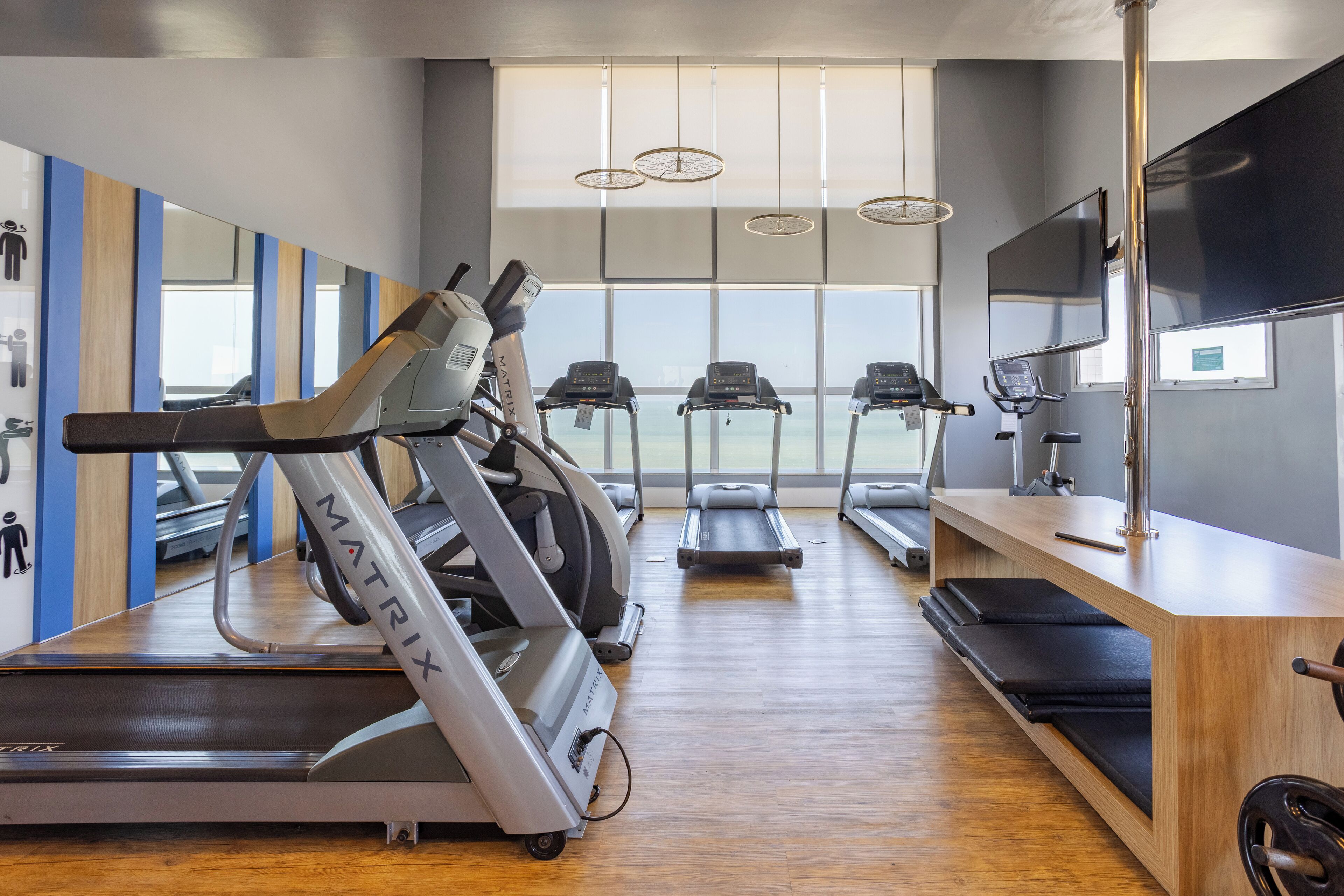 A modern gym with treadmills, a stationary bike, and a TV screen.