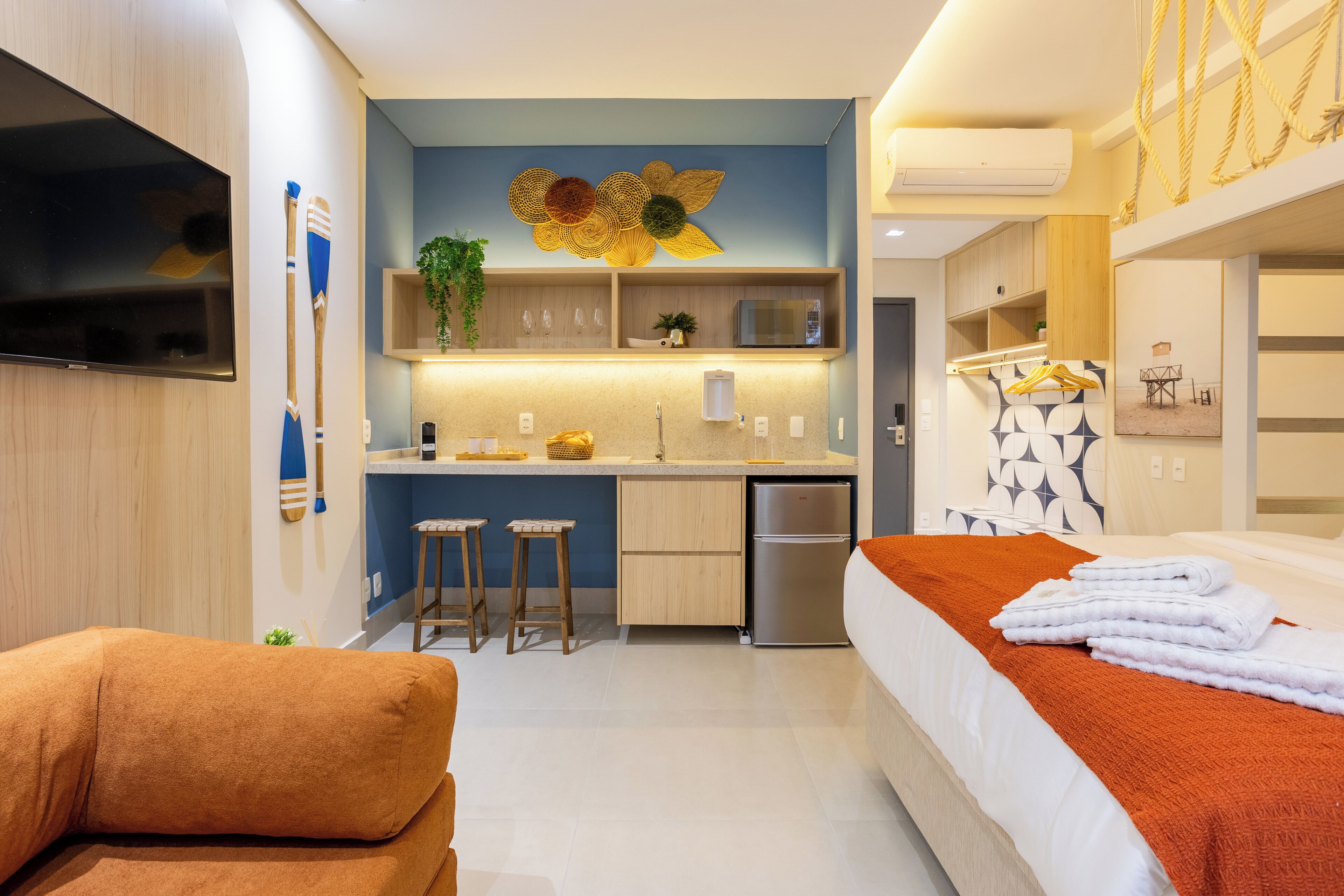 Una habitación de hotel moderna con cama, sofá, cocina y televisor.