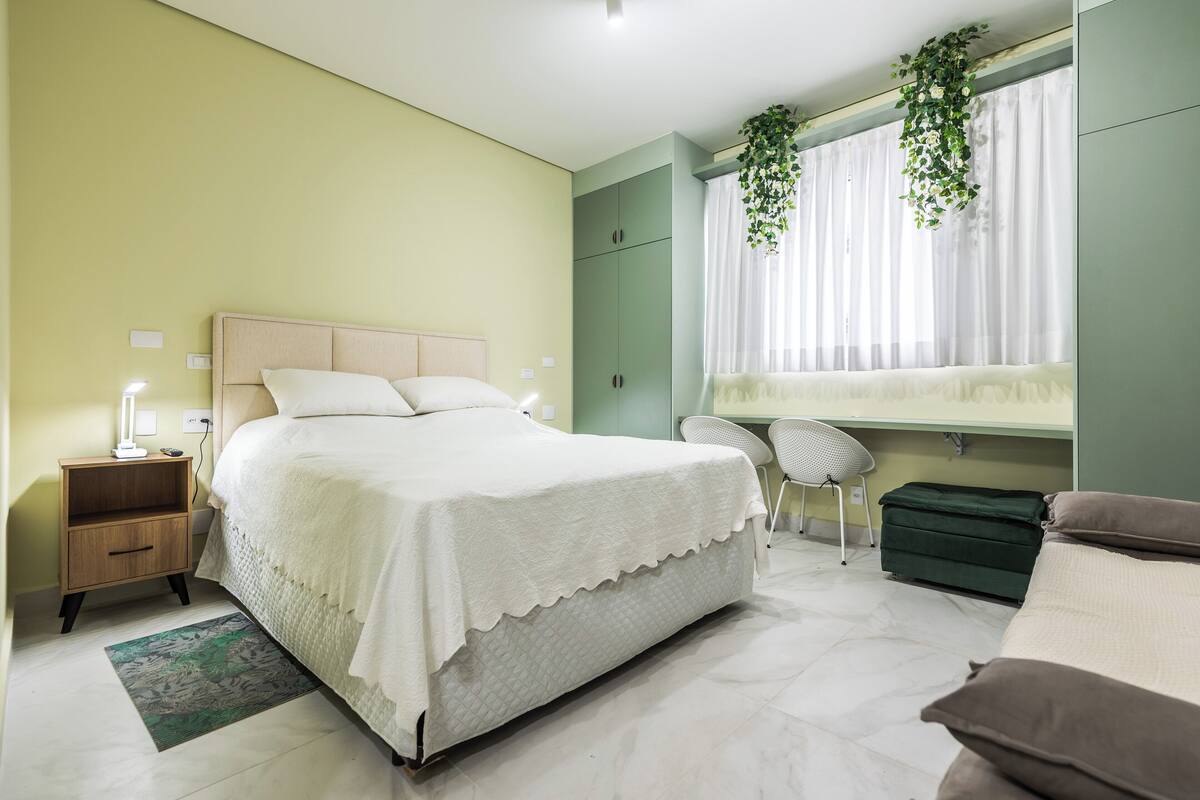 A bedroom with a bed, bedside table, chair, and wardrobe.