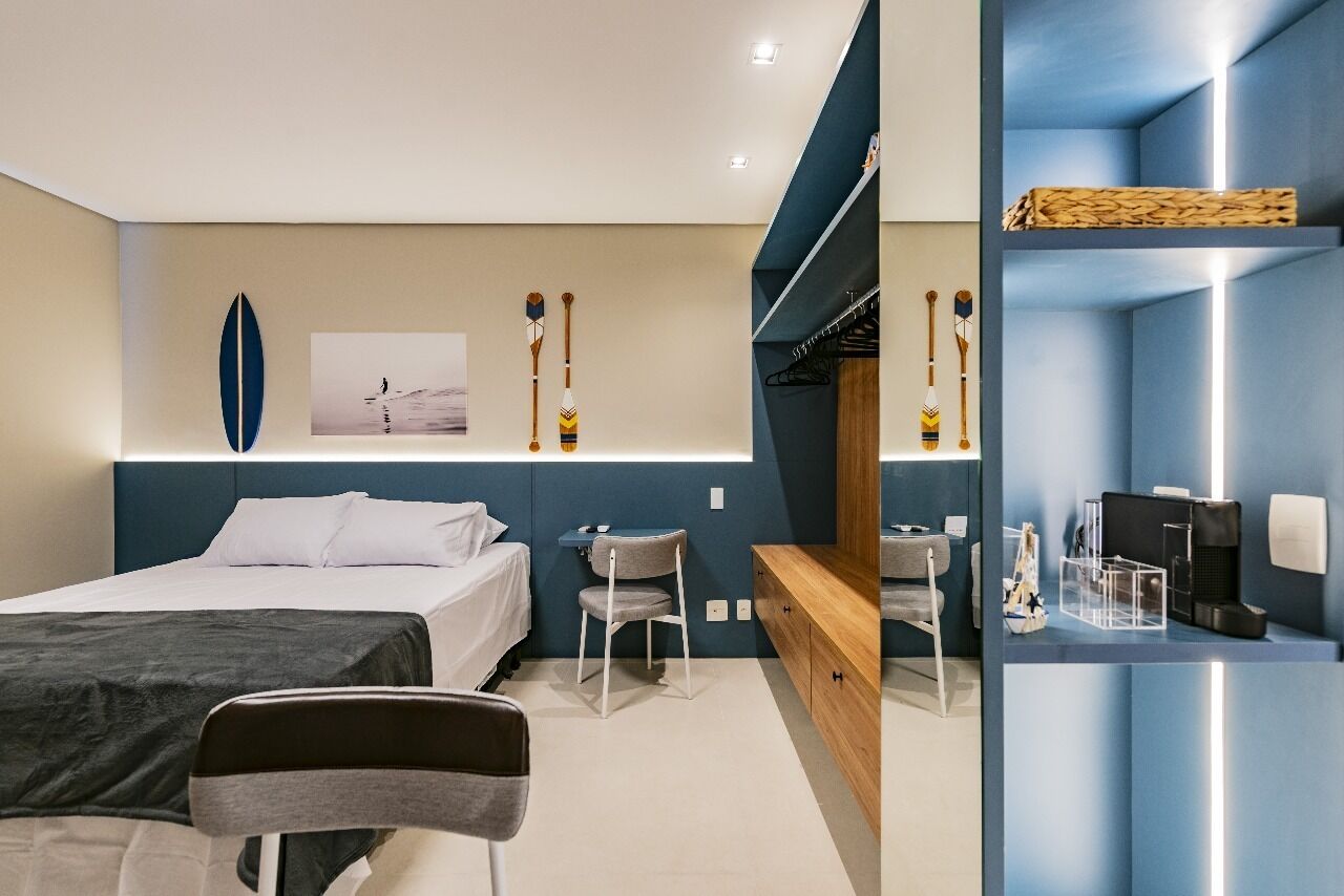 A modern hotel room with a bed, a desk, and a seating area.