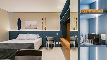 A modern hotel room with a bed, a desk, and a seating area.