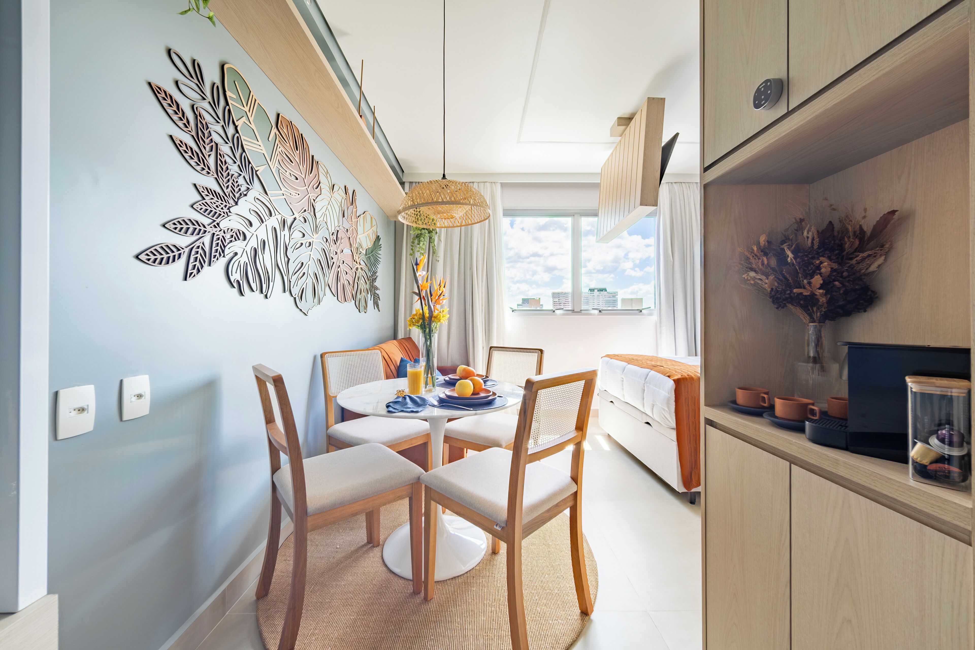 A modern dining area with a round table, chairs, and a decorative wall piece.