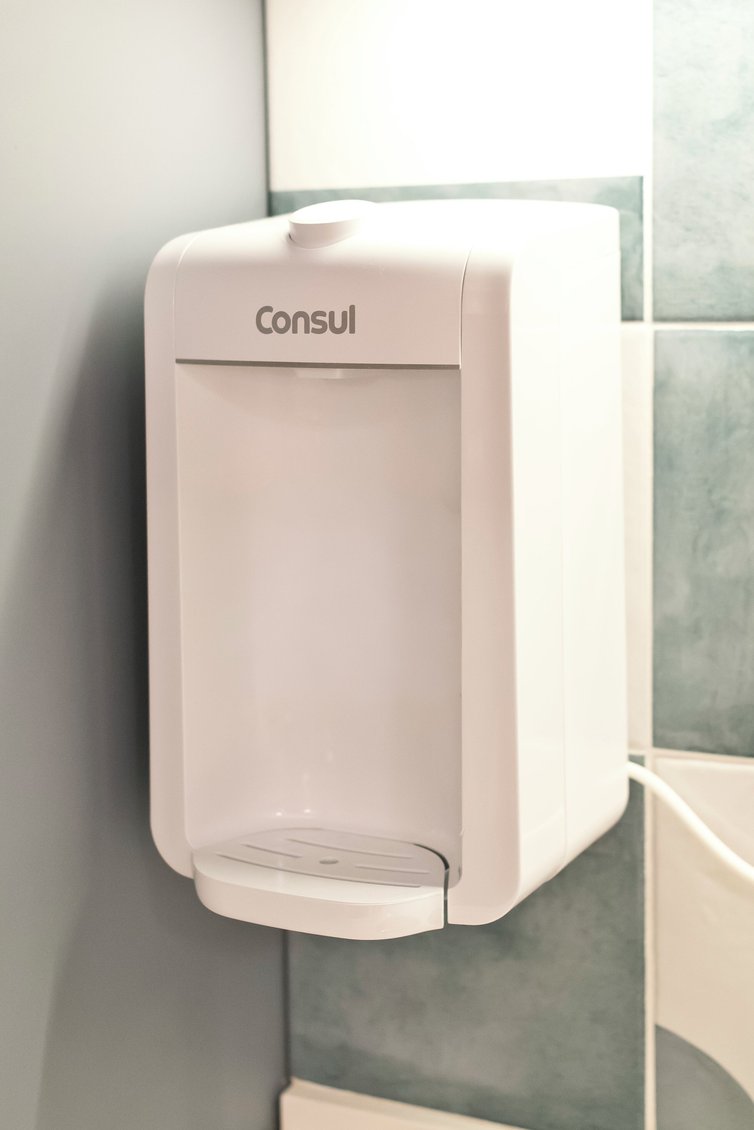 Dispensador Consul blanco instalado en la pared, en un baño.