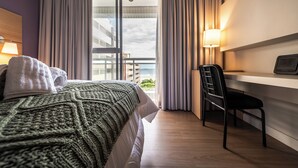 Hotellihuone, jossa on sänky, työpöytä, tuoli ja näkymä ulos.