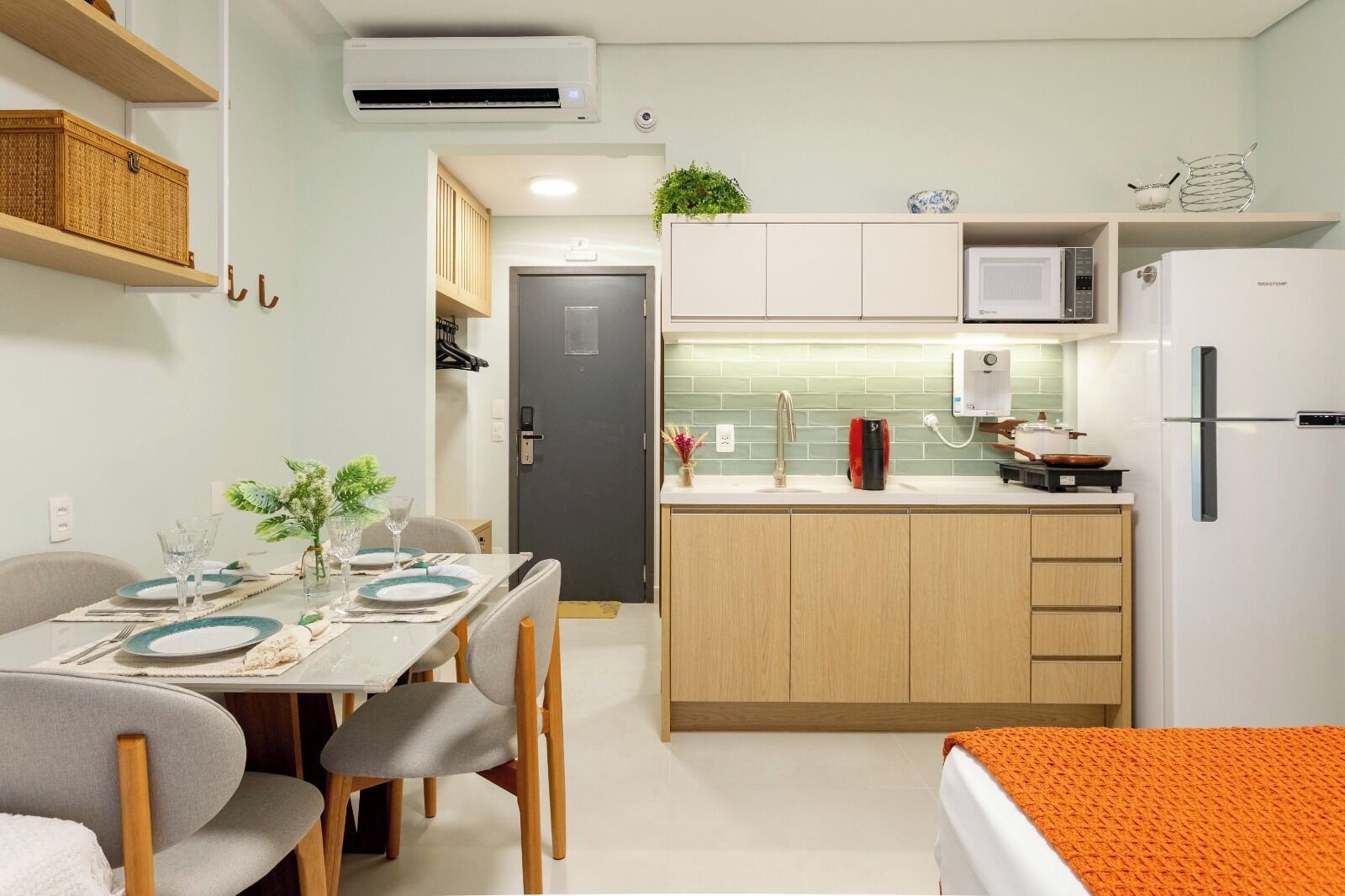 A compact kitchen with a dining area, a microwave, a refrigerator, and a sink.