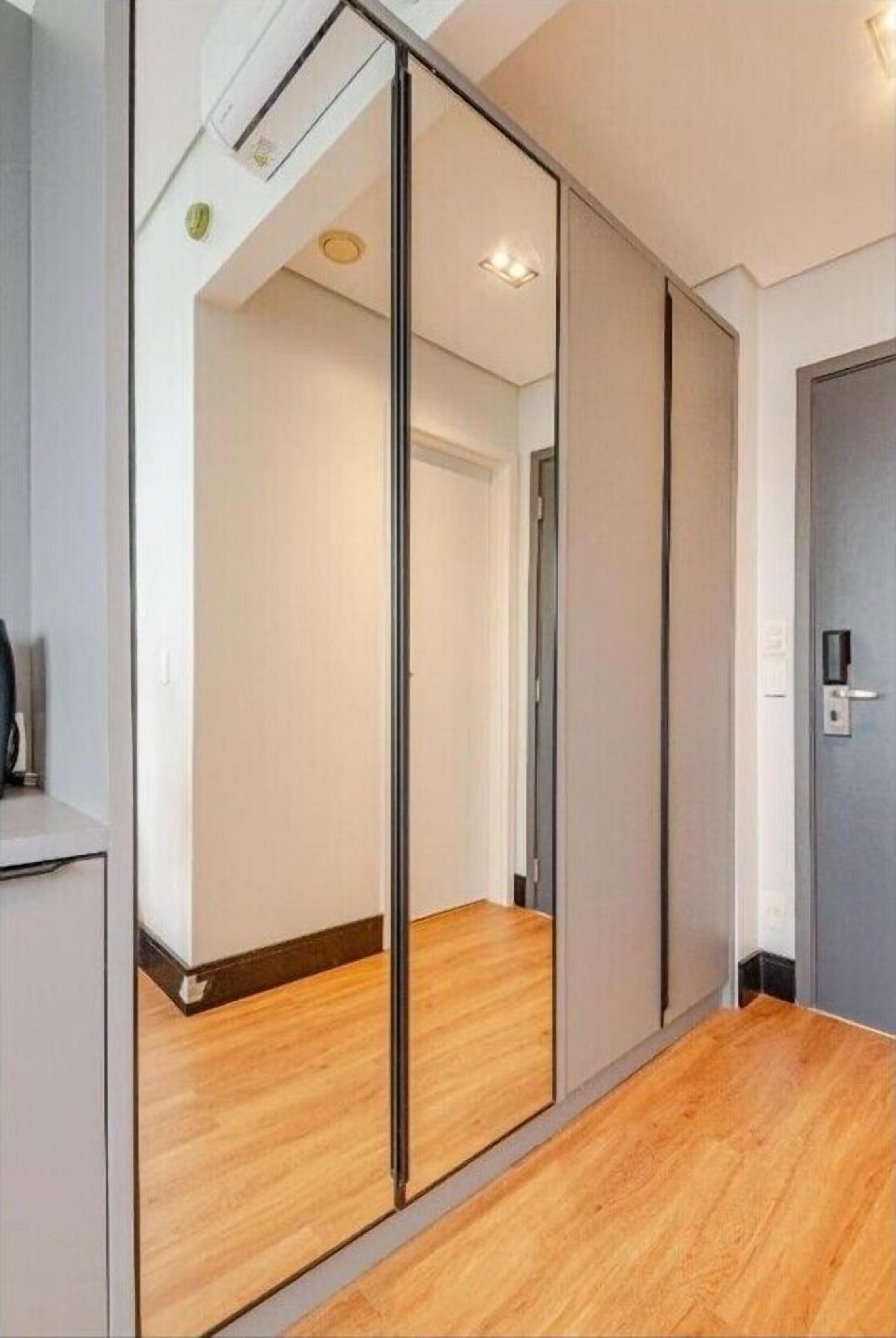 Una habitación con puerta corredera, suelo de madera y un interruptor de luz en la pared.