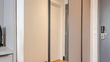 Una habitación con puerta corredera, suelo de madera y un interruptor de luz en la pared.