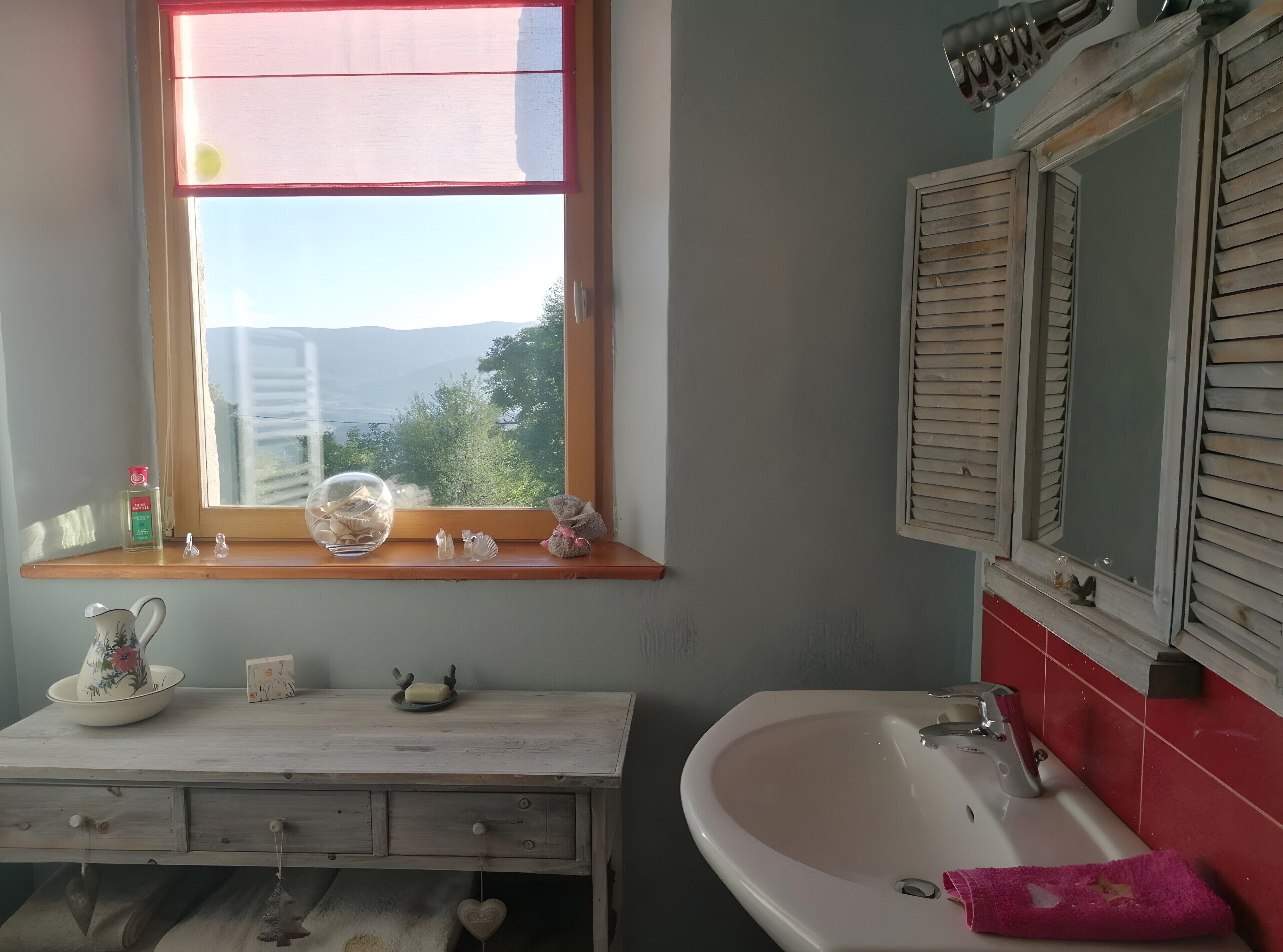 Une salle de bain avec une fenêtre, un lavabo et un miroir.
