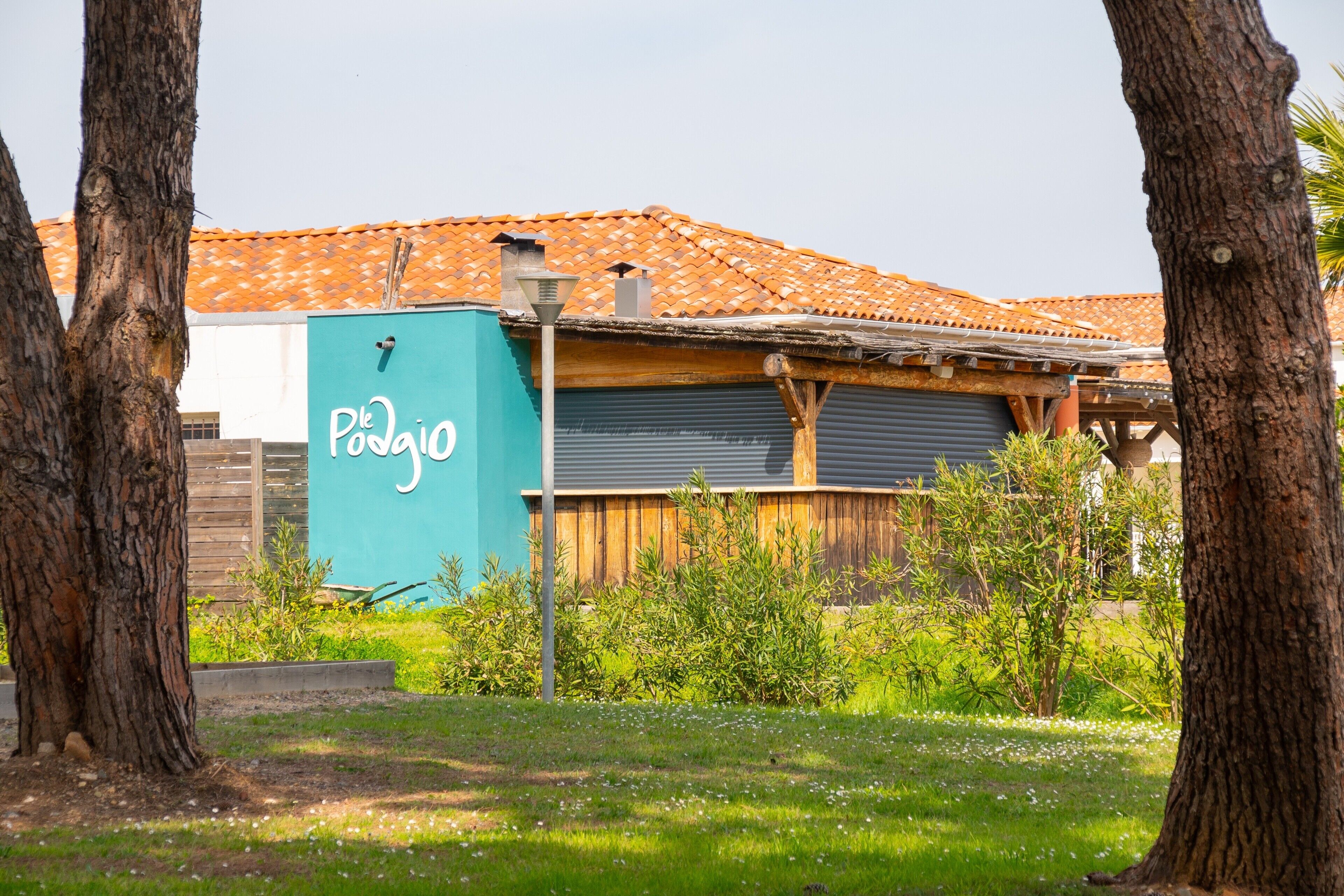 A building with a tiled roof, a blue utility box with 'Pondago' written on it, and a wooden fence.
