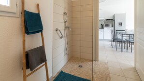 A shower with a glass door, a towel rack, and a small rug on the floor. - Apartment 'Chez Lena' 100m from the Sea with Shared Pool, Wi-Fi, and Air Conditioning (Poggio-Mezzana)