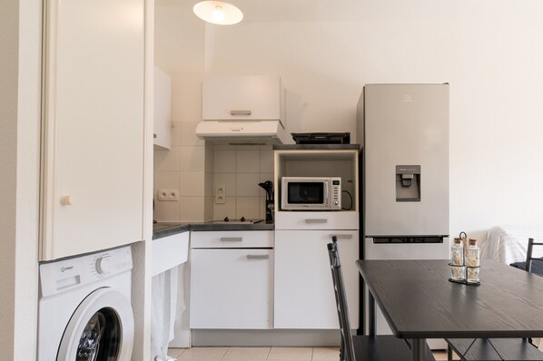 Une cuisine compacte équipée d’un lave-linge, d’un four à micro-ondes et d’un réfrigérateur.