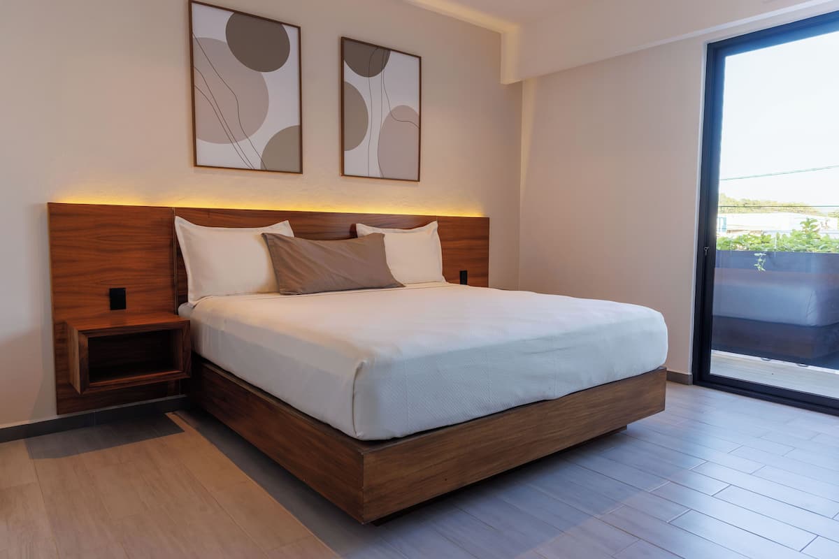 Ein modernes Schlafzimmer mit einem hölzernen Bettgestell, weißer Bettwäsche und zwei abstrakten Wandbildern.