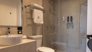A modern bathroom with a large sink, toilet, and glass-enclosed shower. - MARUVA Hotel Ejecutivo (Tecomán)