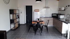 Eine kleine Küche mit Esstisch, Stühlen, einer Mikrowelle und einem Spülbecken.