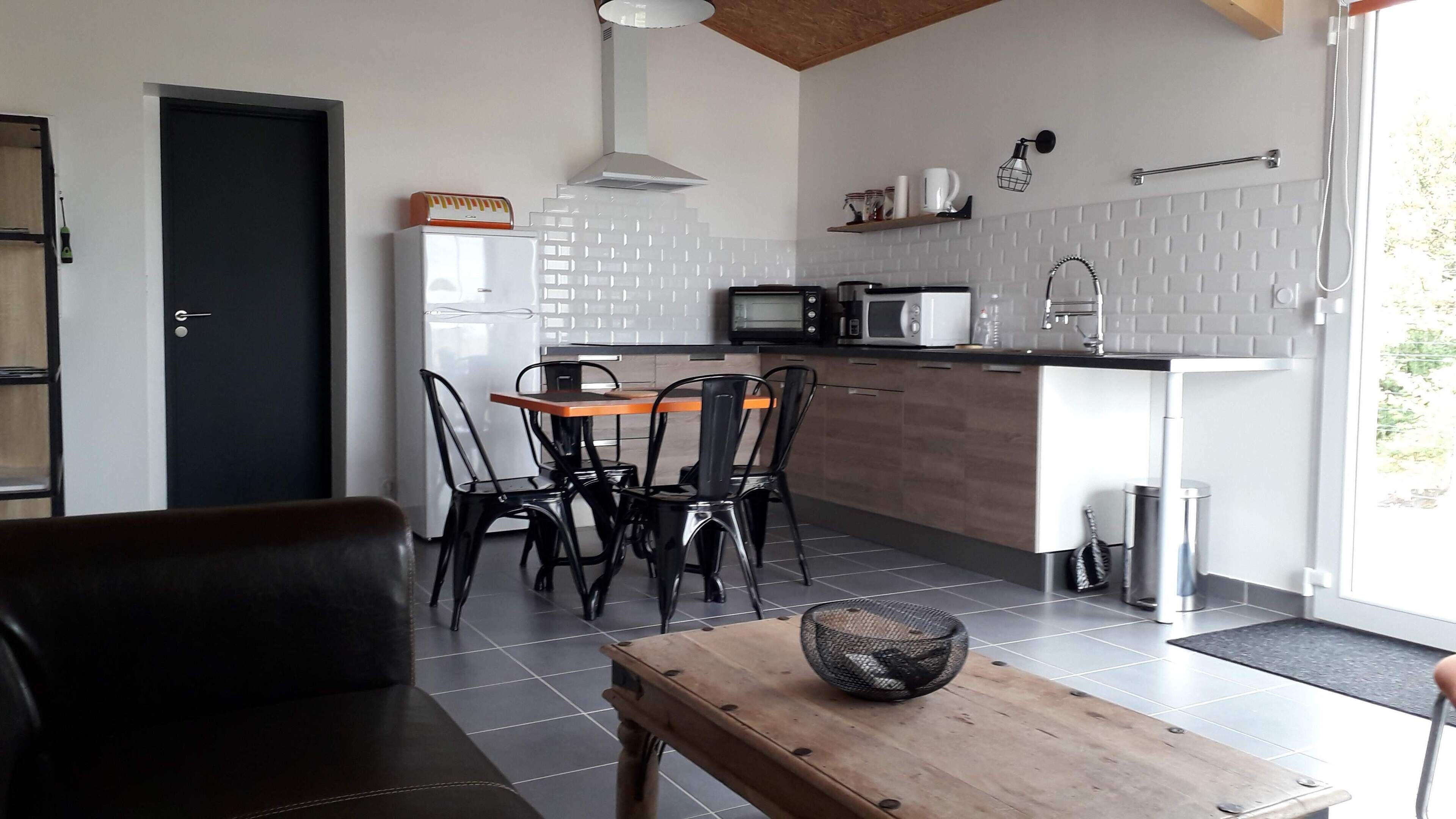 Una cucina compatta con forno a microonde, tostapane e lavello. C'è un'area pranzo con tavolo e sedie.